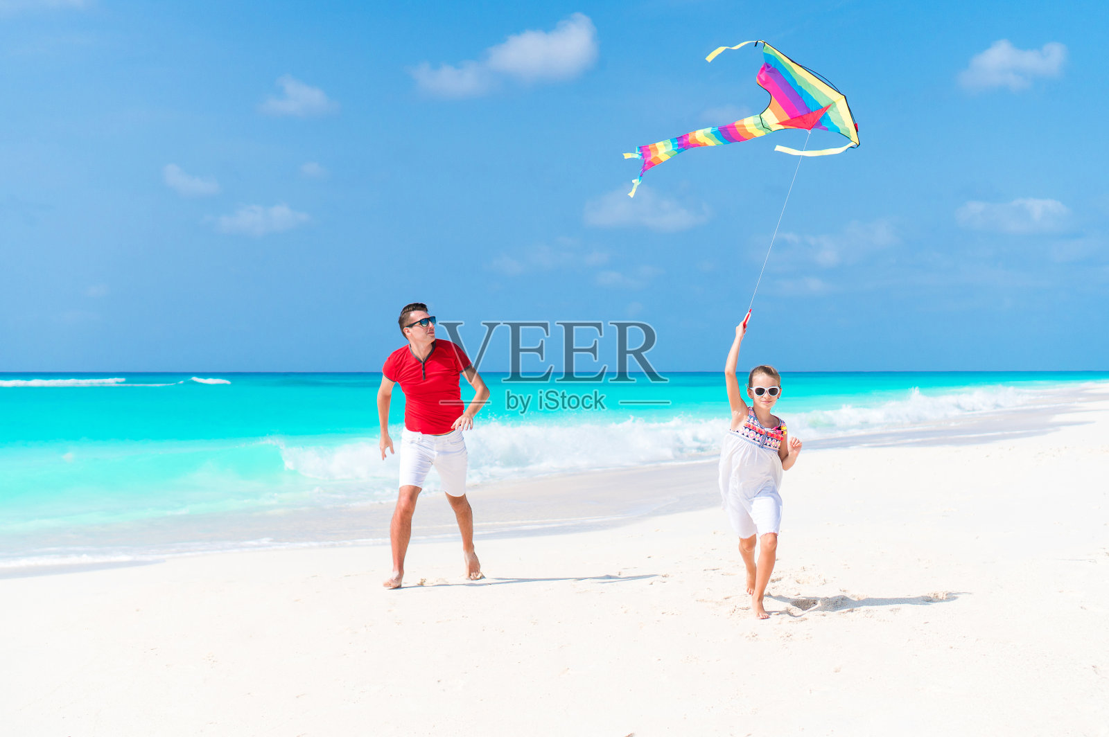 快乐的父亲和可爱的小女儿一起在热带海滩放风筝照片摄影图片