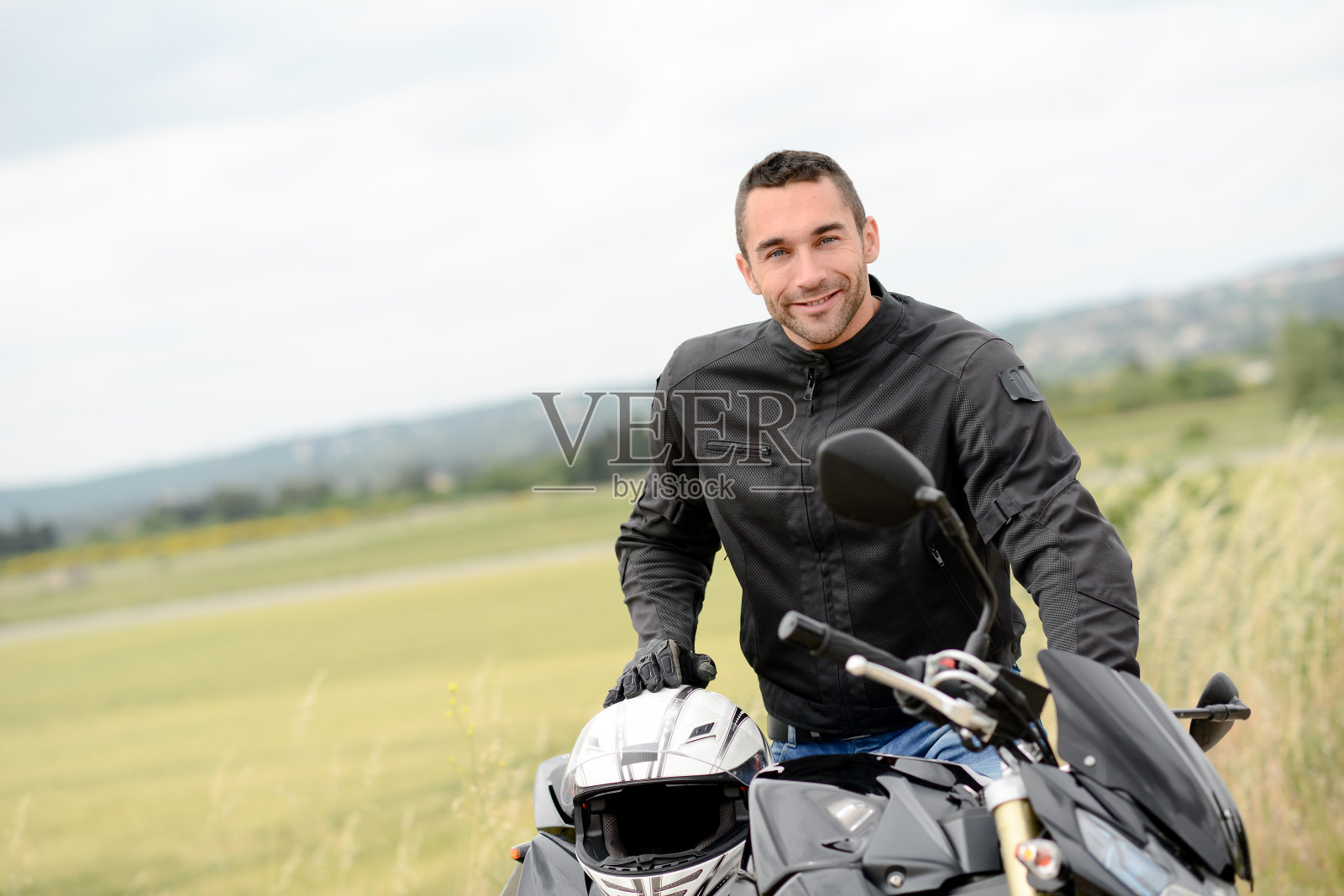 英俊的年轻人骑着他的黑色摩托车照片摄影图片