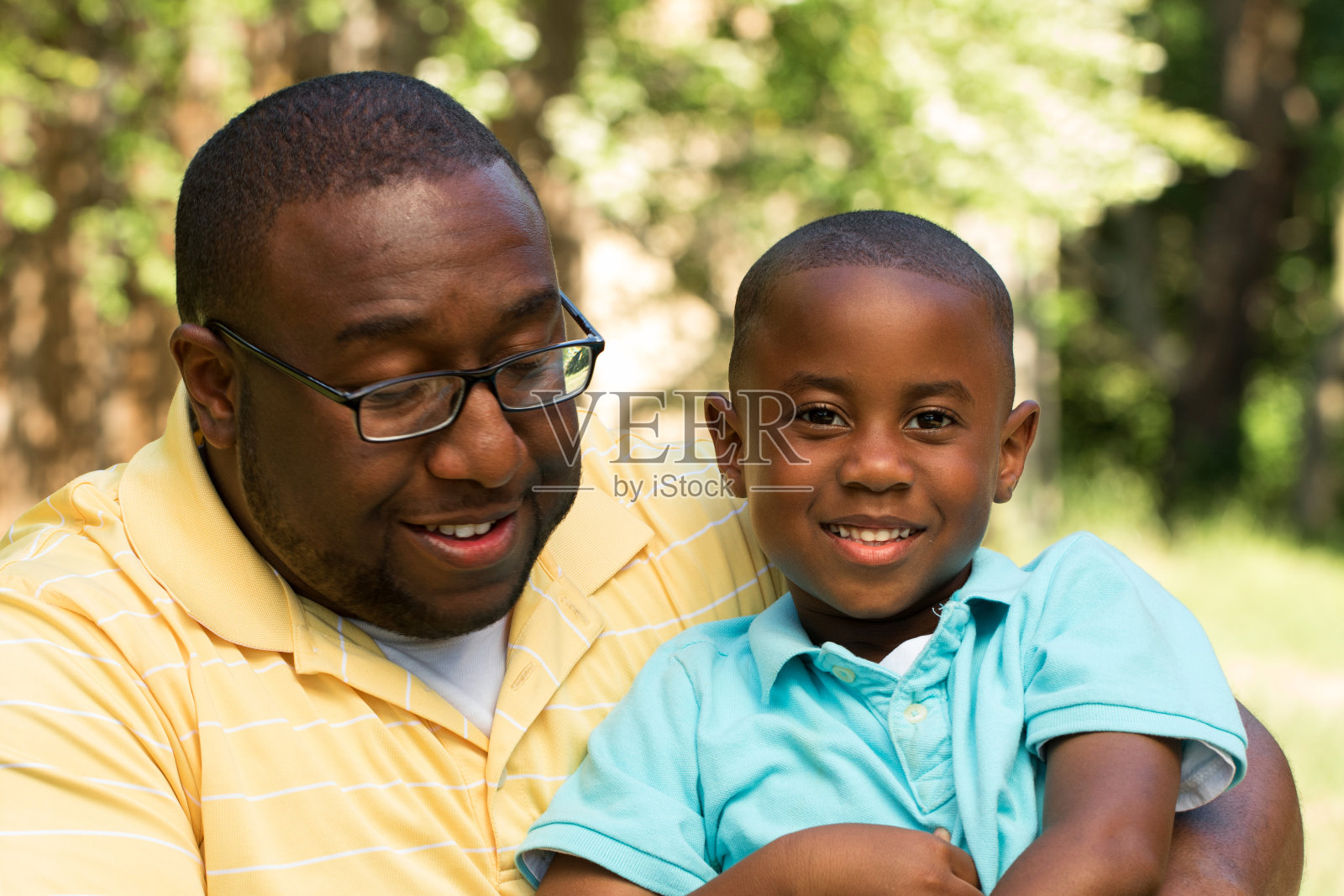 非裔美国人父亲和儿子拥抱大笑。照片摄影图片