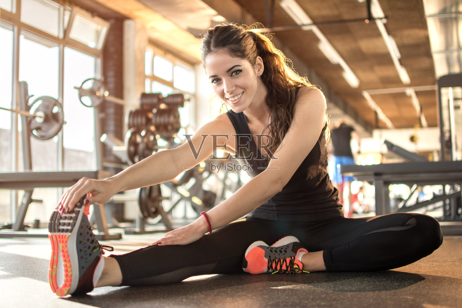 年轻的运动女性在健身房伸展。照片摄影图片