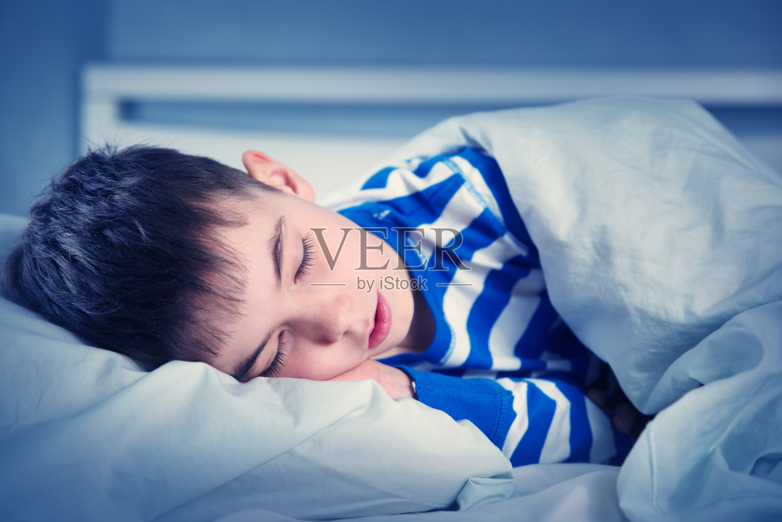 穿着睡衣睡在床上的男孩照片摄影图片