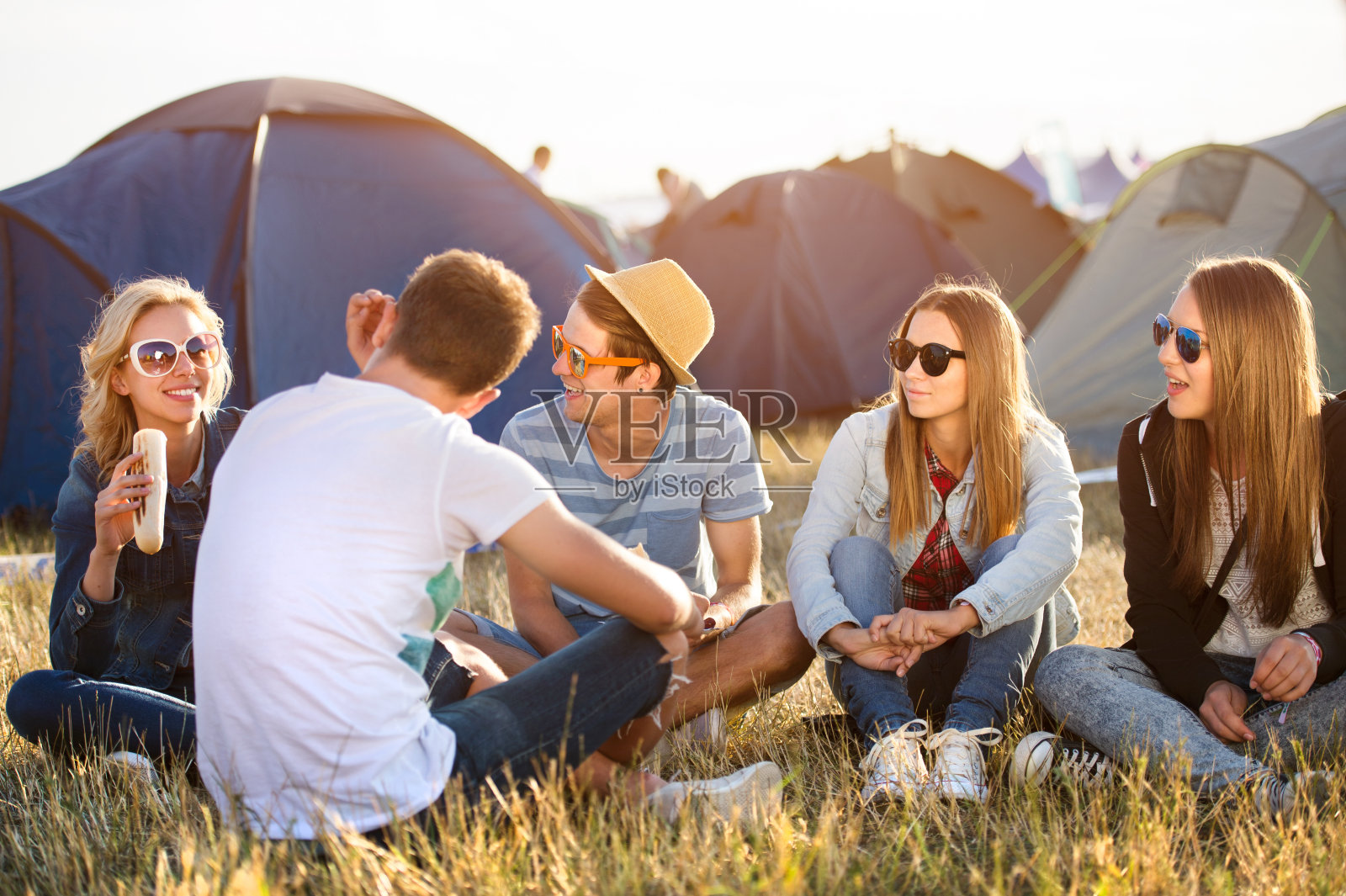 青少年们坐在帐篷前的地上吃东西照片摄影图片