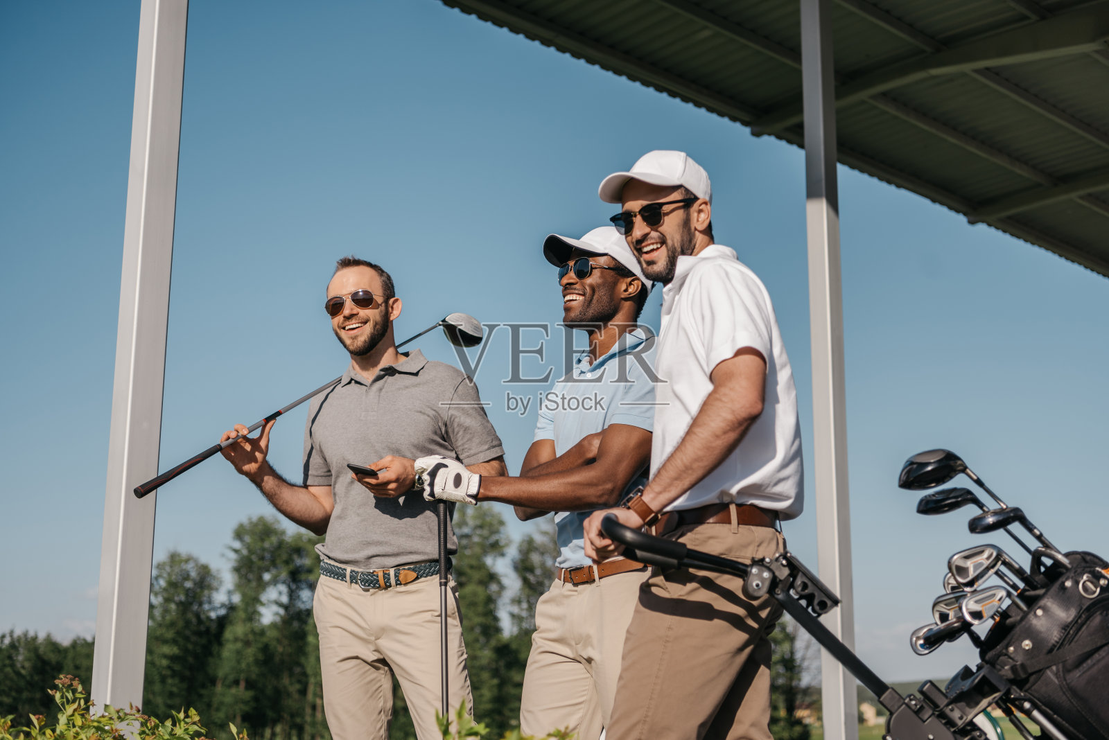 三个戴着太阳镜的男人在户外拿着高尔夫球杆，面带微笑照片摄影图片