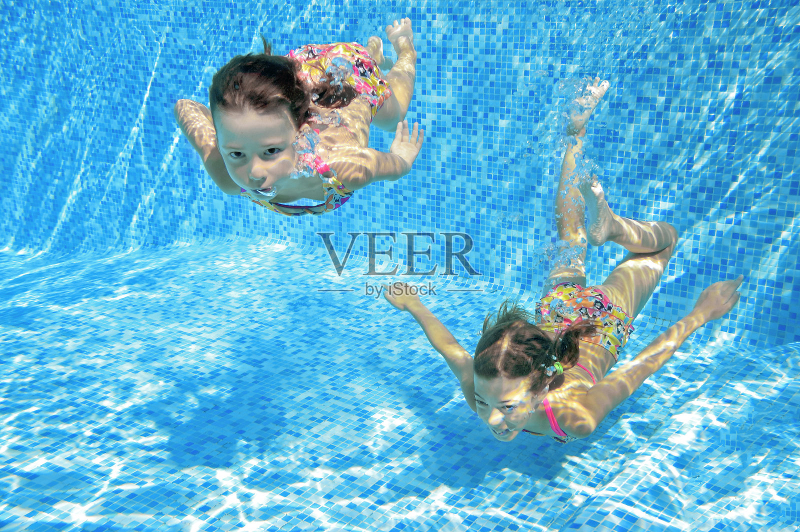 儿童游泳在游泳池水下，快乐活跃的女孩有乐趣在水，儿童健身和运动在积极的家庭度假照片摄影图片