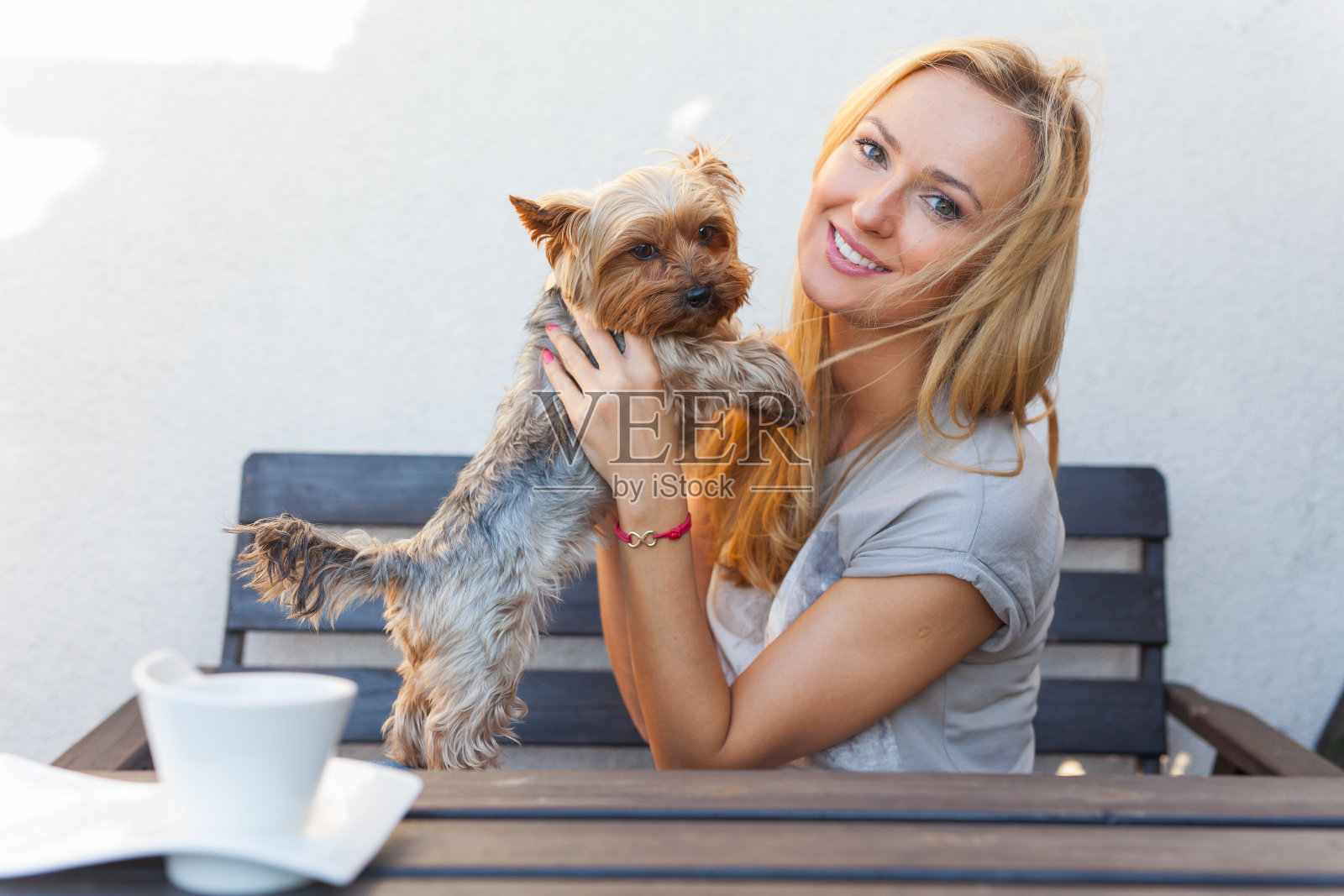 性感的金发女人坐在木凳上和她的狗。照片摄影图片