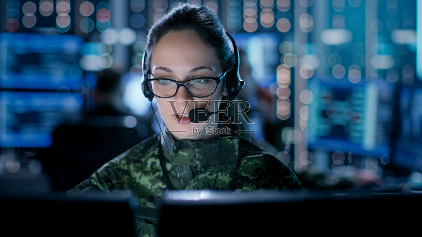 女性IT工程师在政府监控机构的台式电脑上工作。在多屏幕显示图形的工作站上的后台人员。照片摄影图片