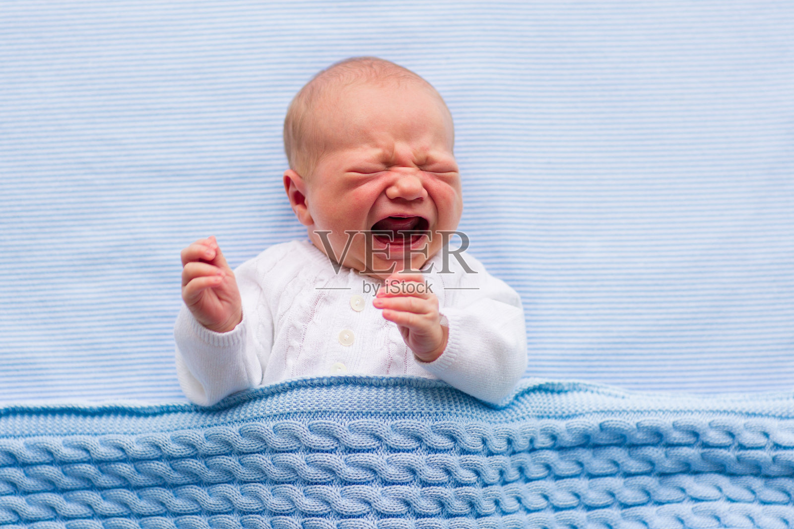 新生的男婴躺在蓝色的毯子上照片摄影图片