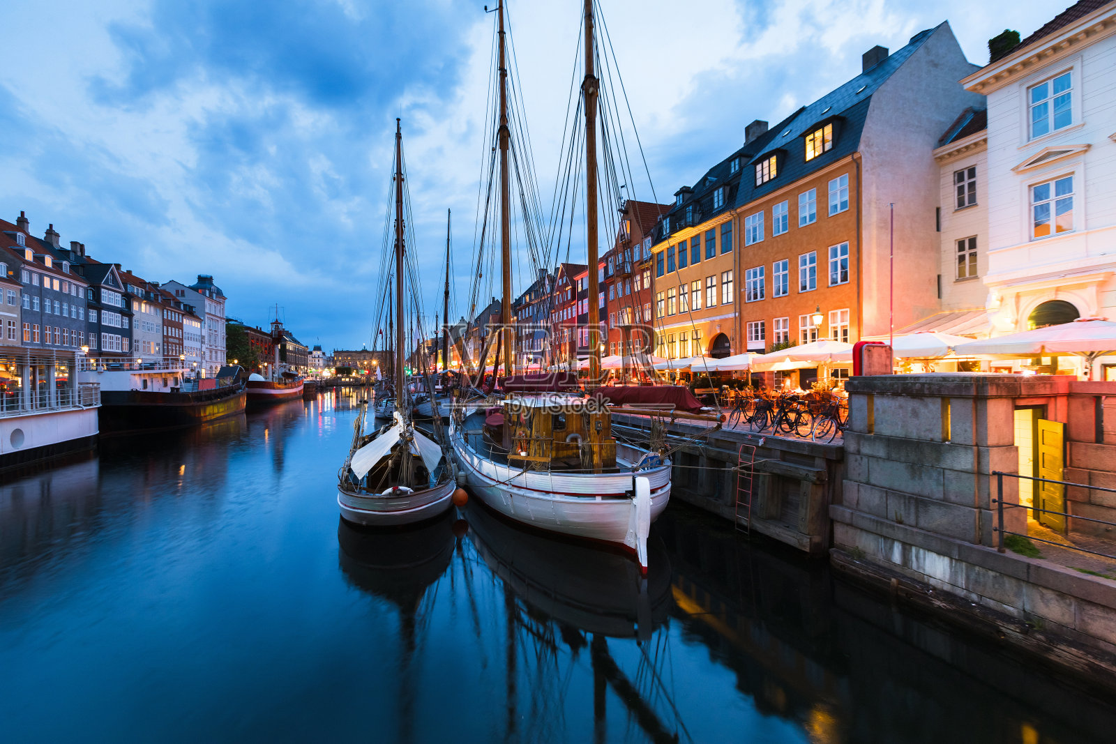 哥本哈根尼哈芬区在蓝色时间有木船，餐馆照片摄影图片