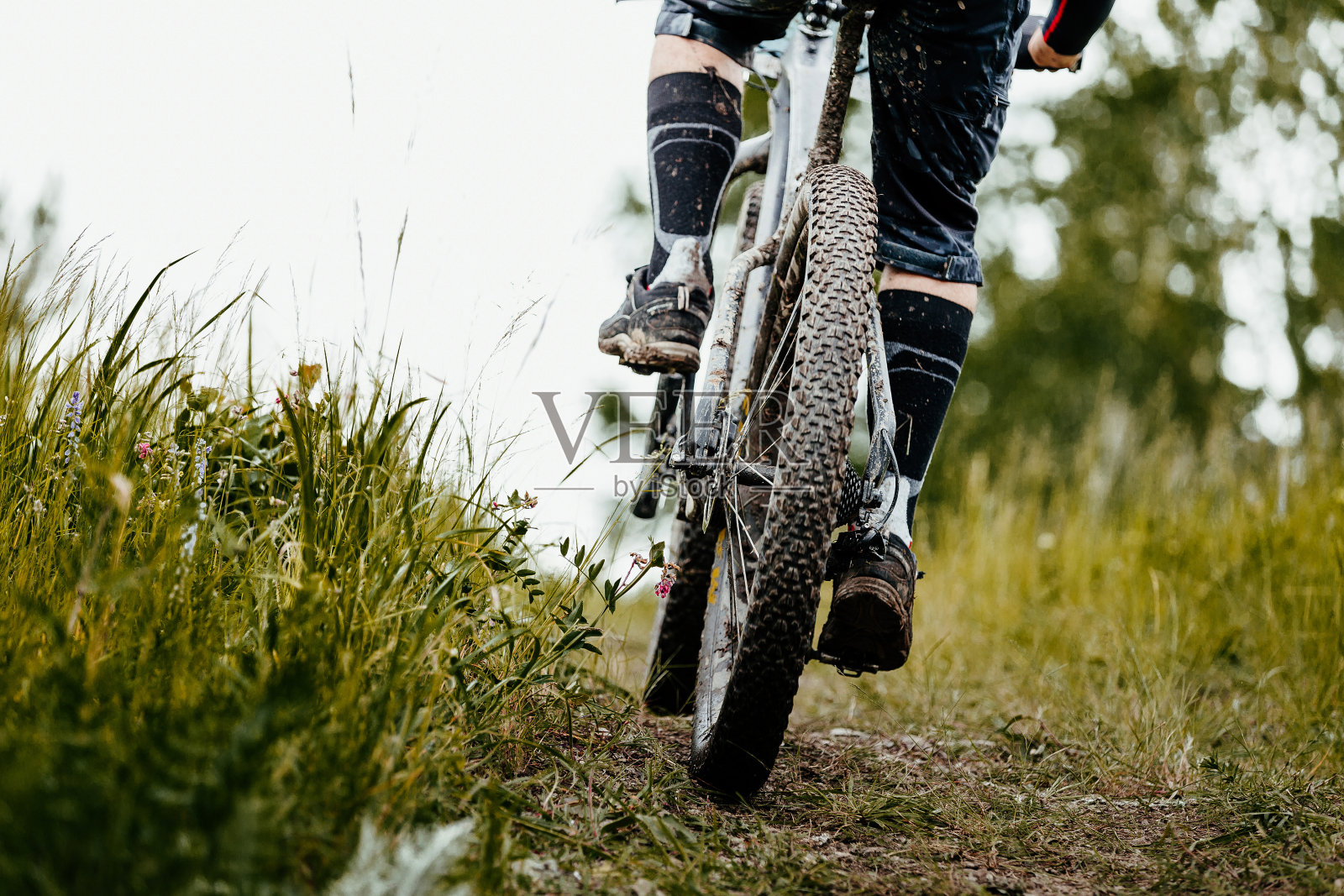 近景泥山自行车车轮和自行车的腿照片摄影图片