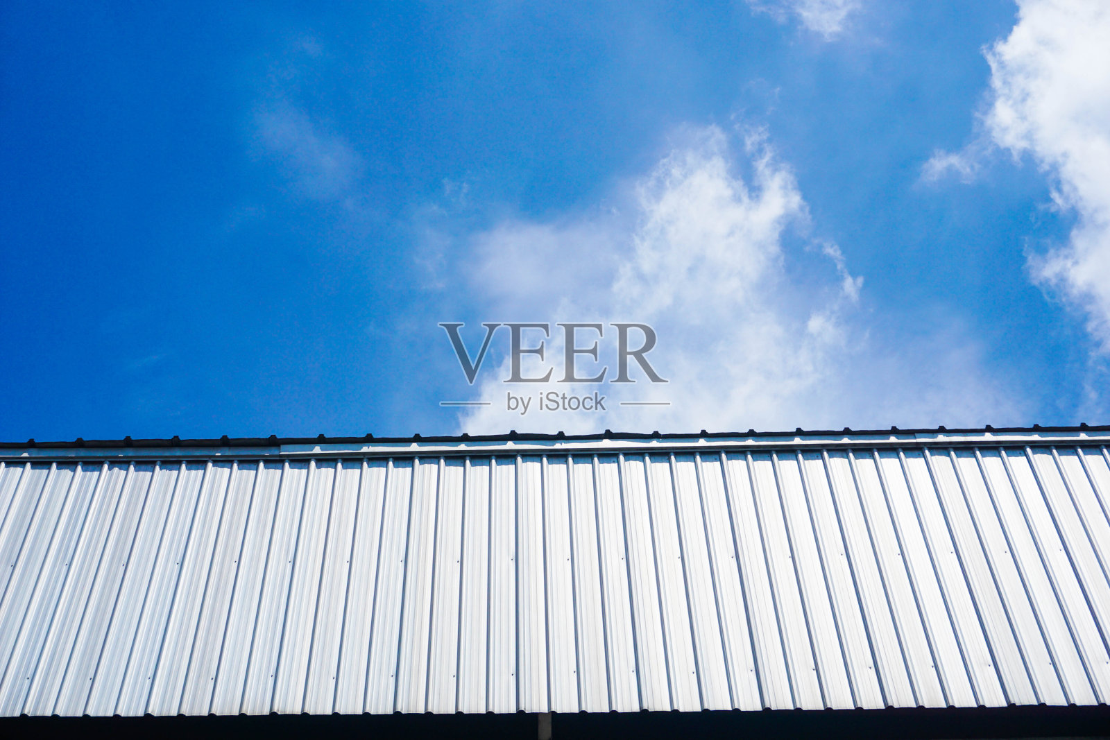 蓝天白云下的工厂或仓库的墙壁和屋顶照片摄影图片