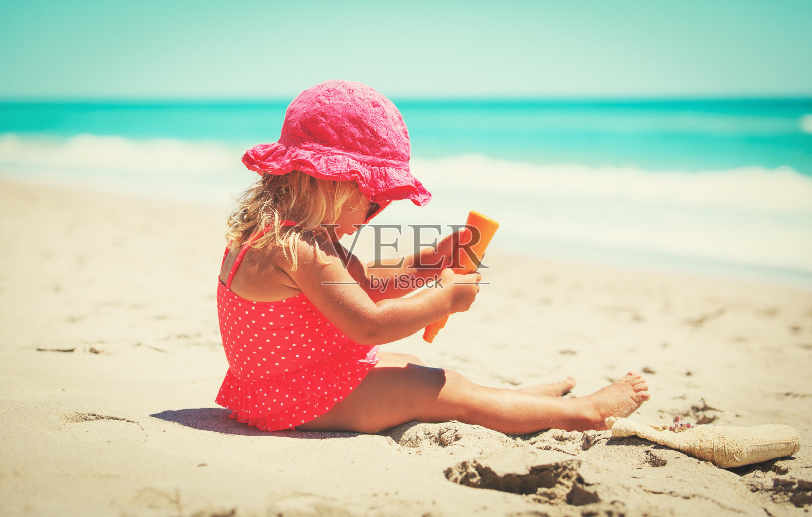 防晒——小女孩在海滩上涂防晒霜照片摄影图片