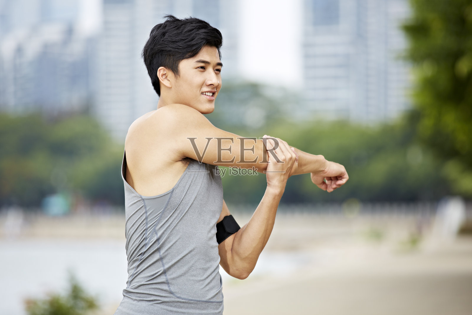 年轻的亚洲慢跑者在公园里伸展手臂照片摄影图片