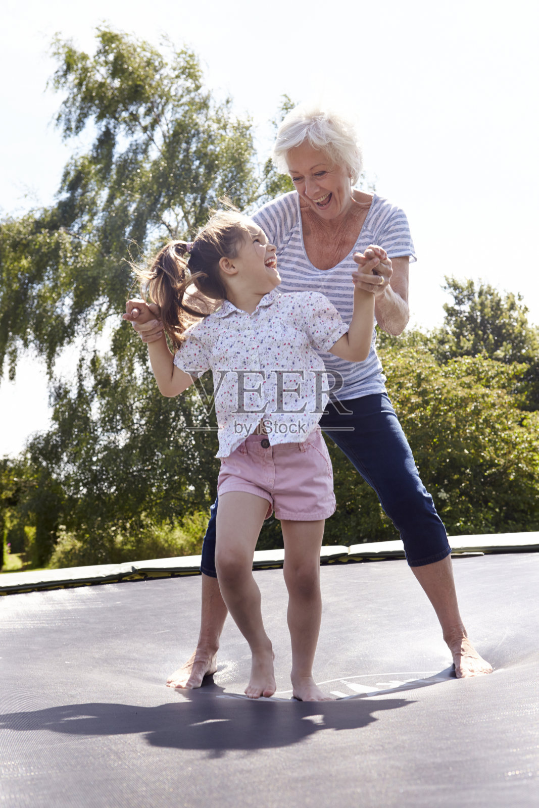 祖母和孙女在蹦床上蹦跳照片摄影图片