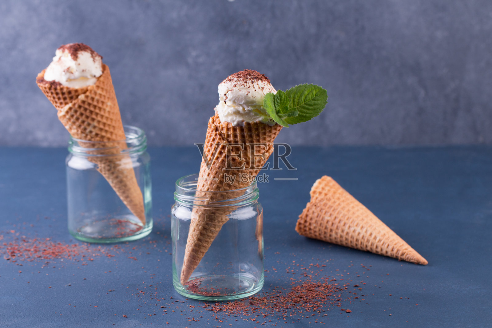 传统的华夫筒冰淇淋在玻璃罐在蓝色的桌子上。装满冰淇淋的蛋卷照片摄影图片