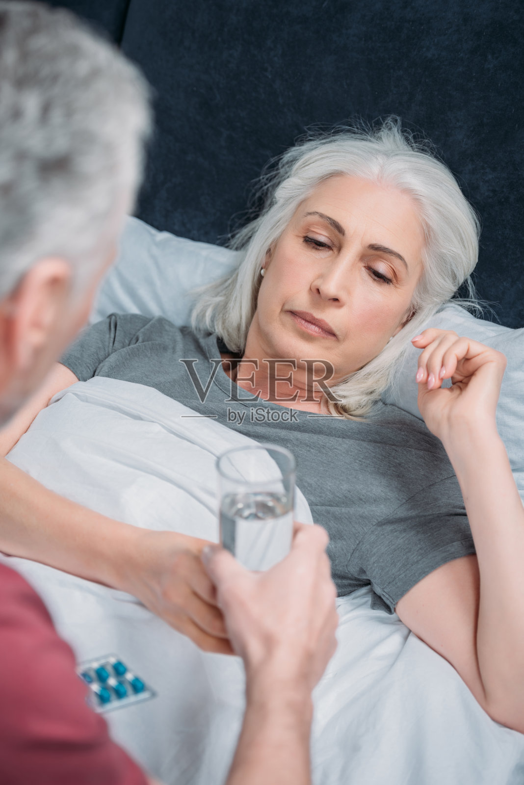 一个男人给卧病在床的妻子一杯水照片摄影图片
