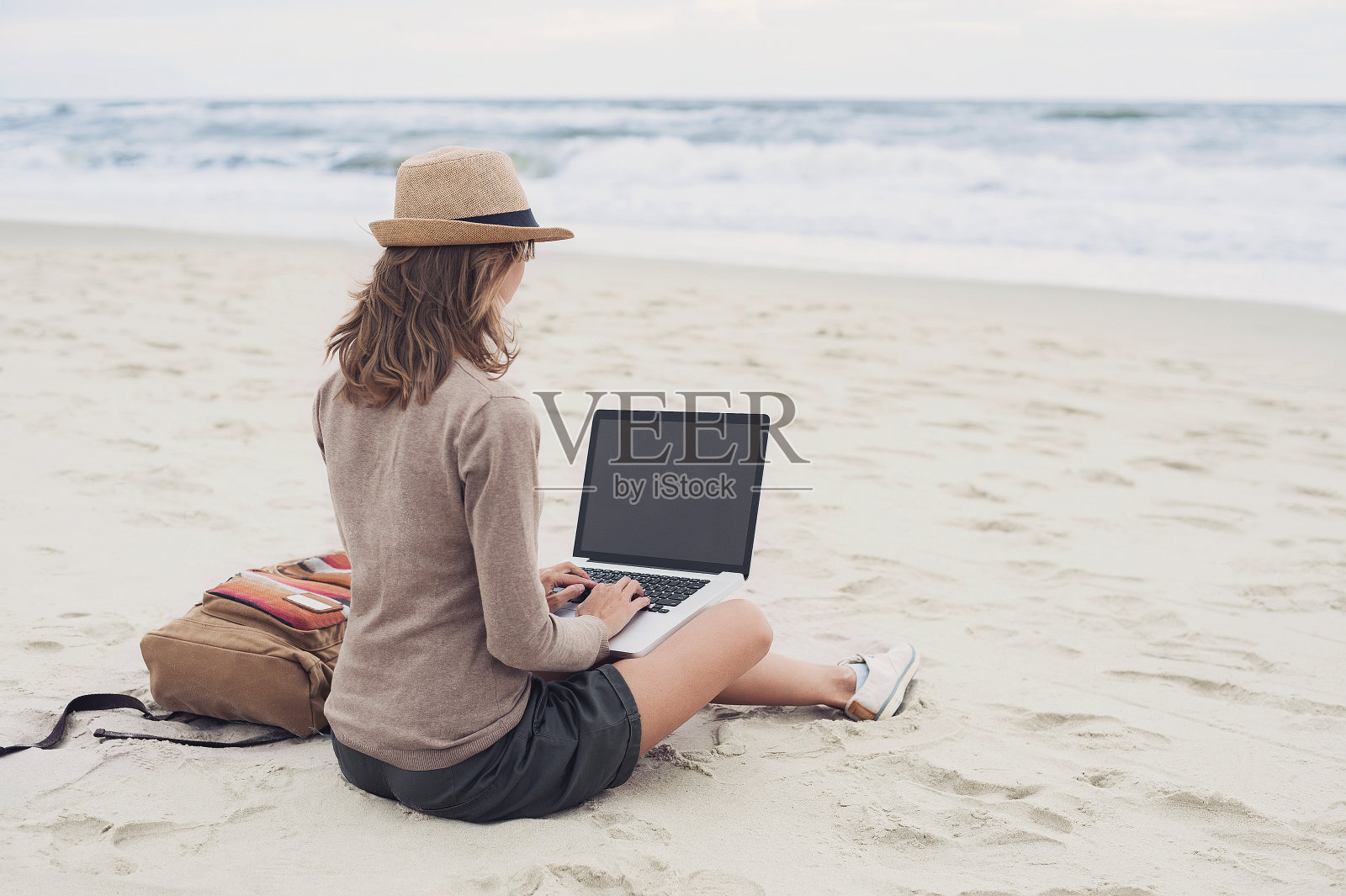 年轻女子在海滩上用笔记本电脑照片摄影图片