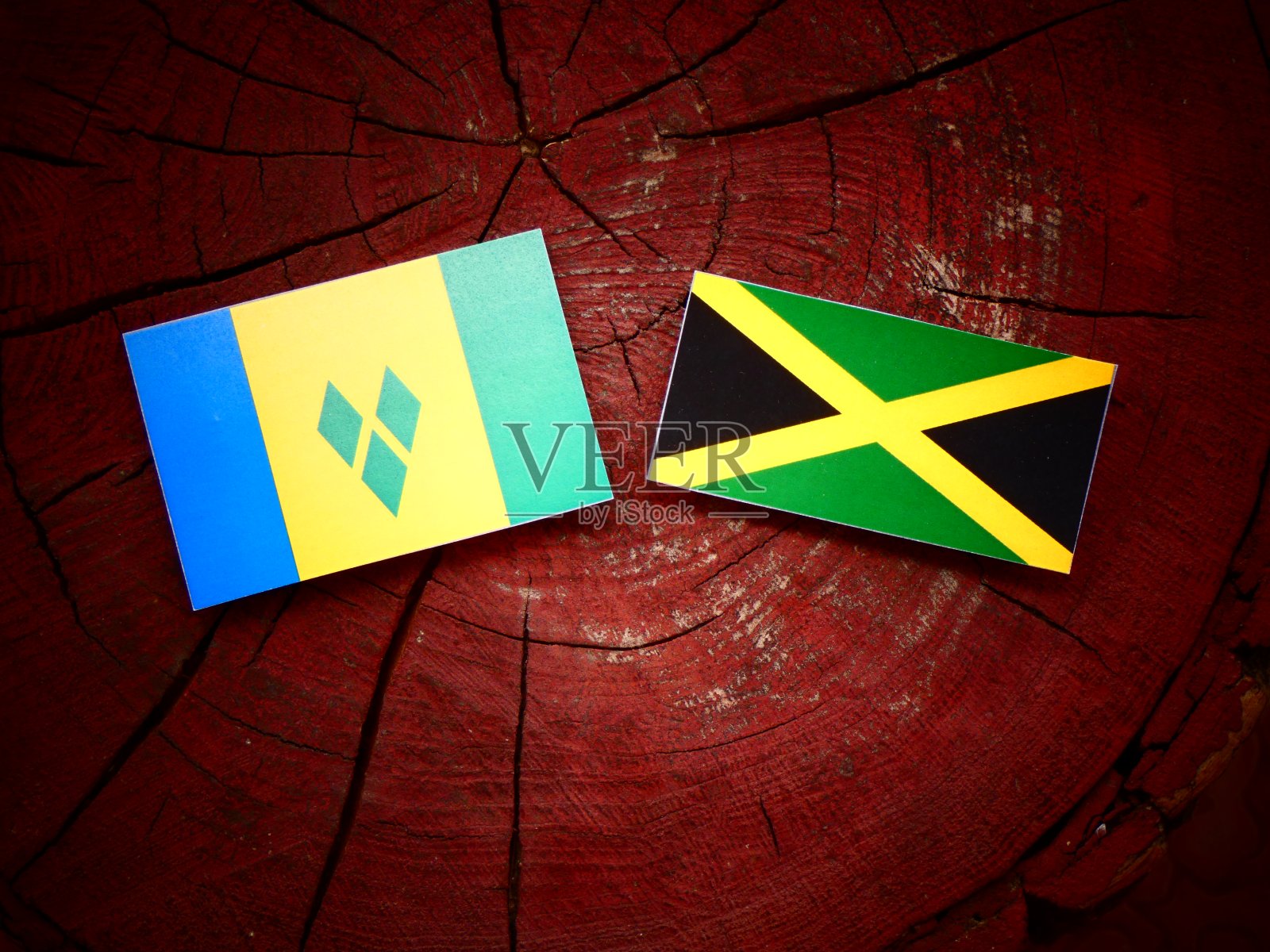 圣文森特和格林纳丁斯的国旗和牙买加国旗在一个孤立的树桩上照片摄影图片