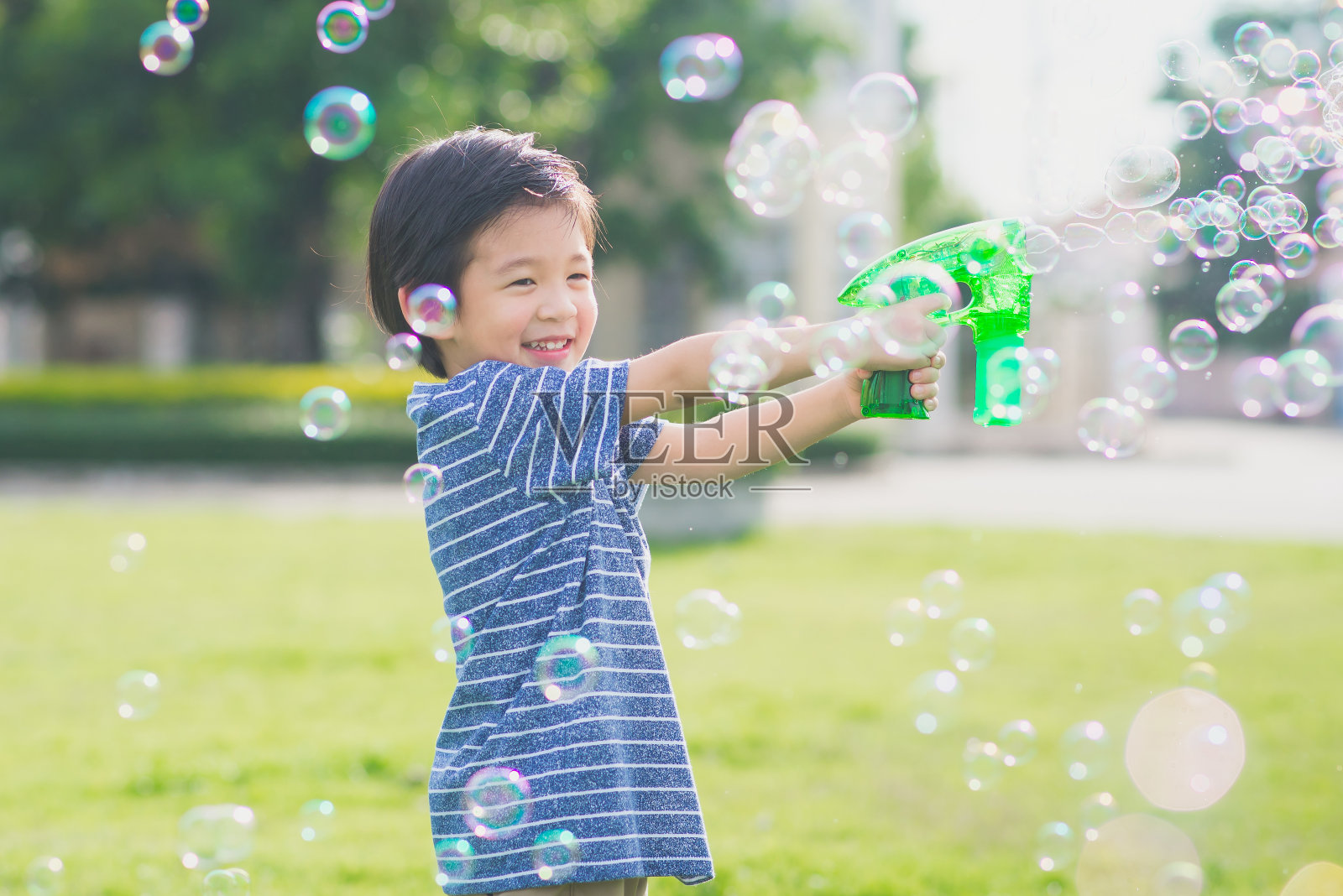 亚洲小孩用泡泡枪射击泡泡照片摄影图片