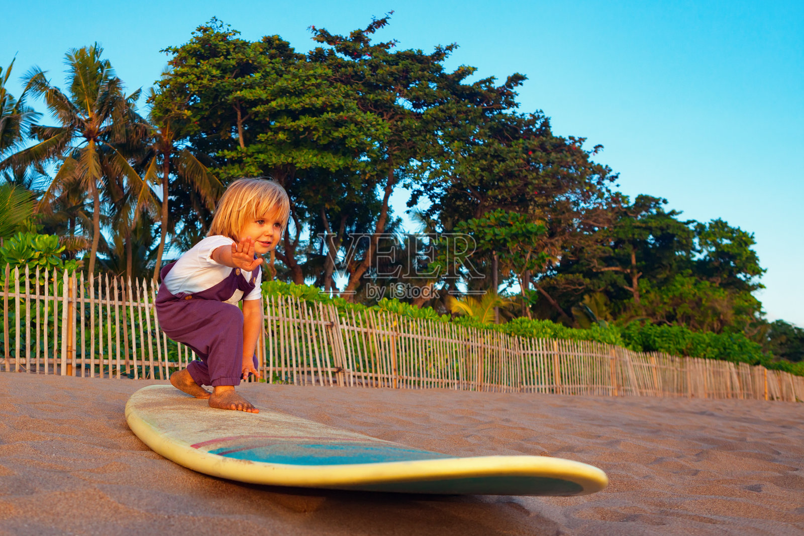 年轻的冲浪者站在冲浪板上玩日落海滩照片摄影图片