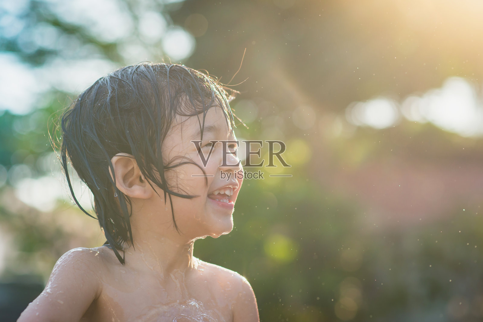 可爱的亚洲男孩玩水从软管户外照片摄影图片