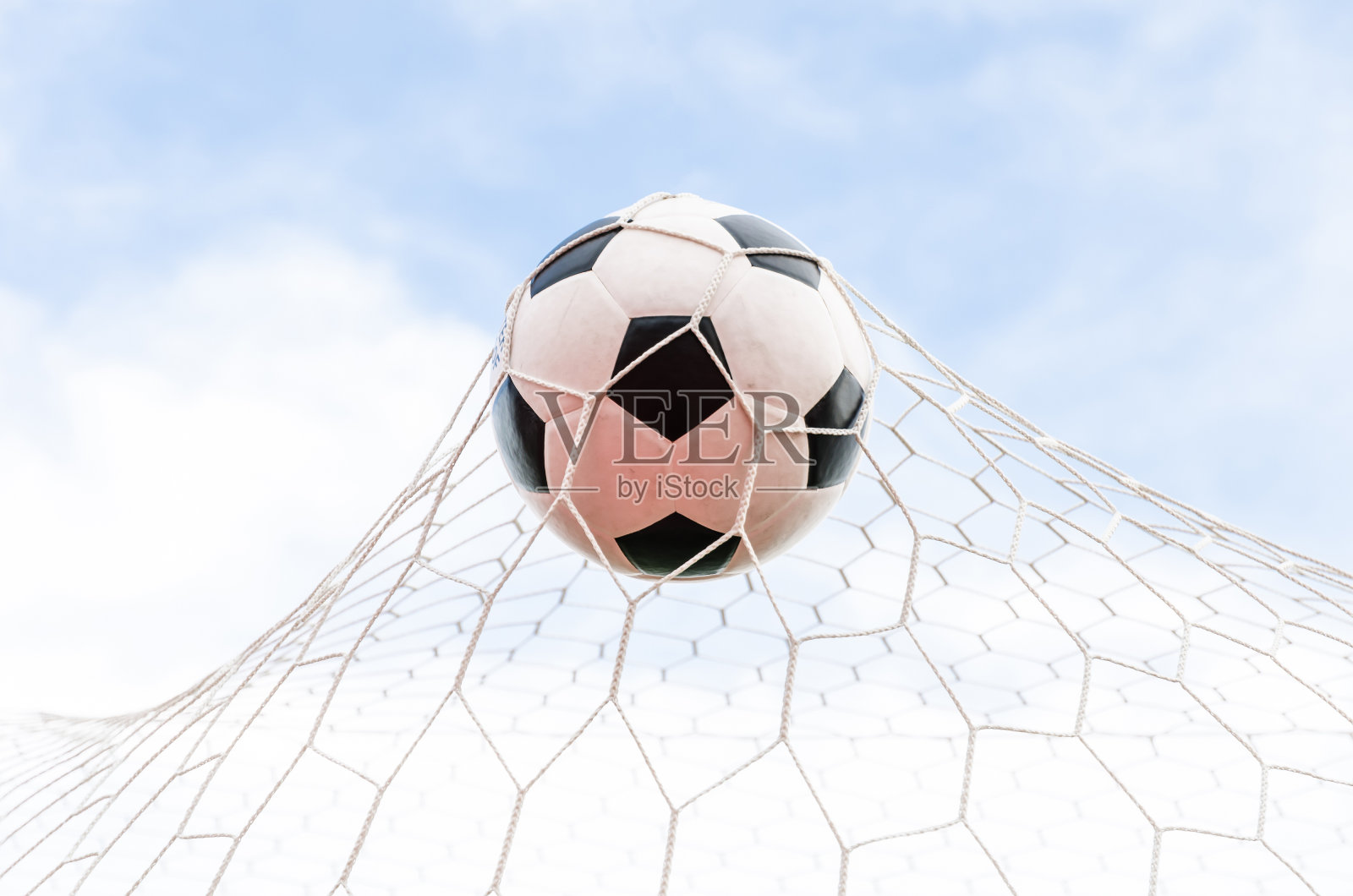 足球在球门网与天空场。照片摄影图片