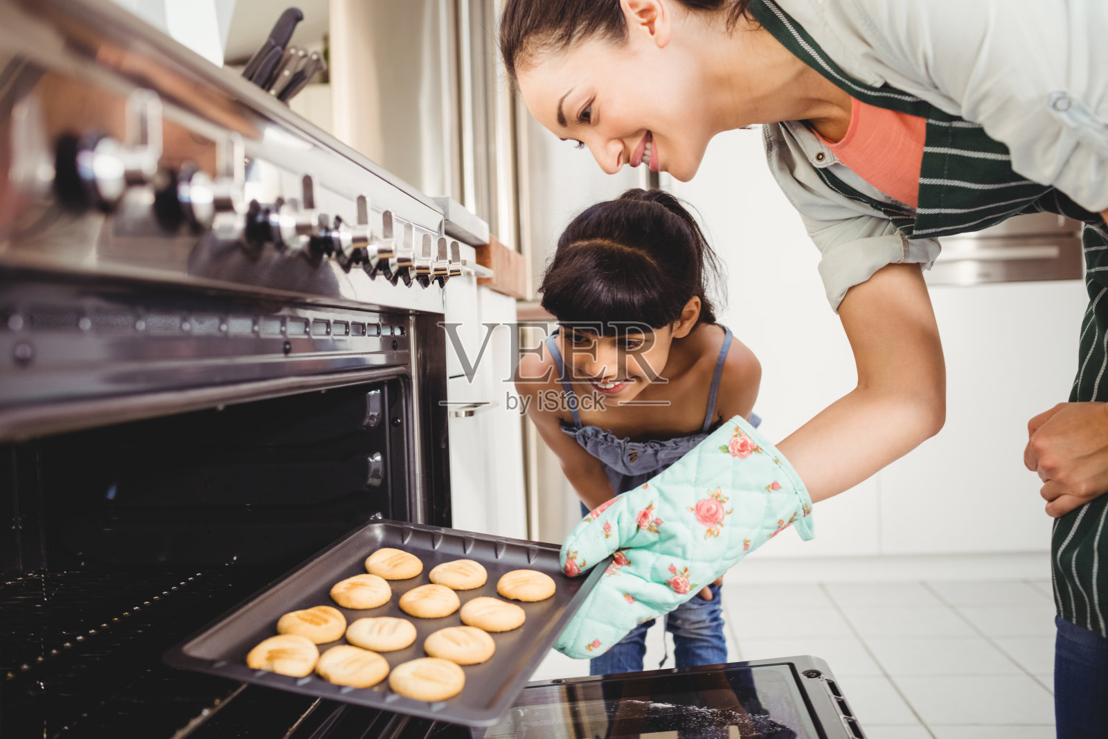 妈妈和女儿在烤箱里放饼干照片摄影图片