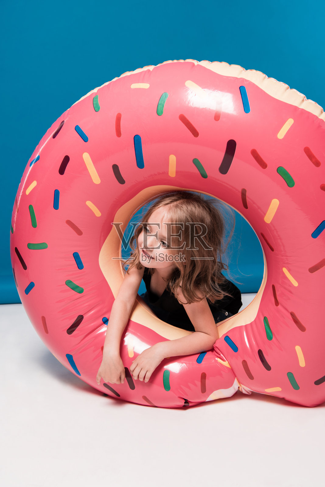 可爱的小女孩玩甜甜圈形状的游泳管照片摄影图片