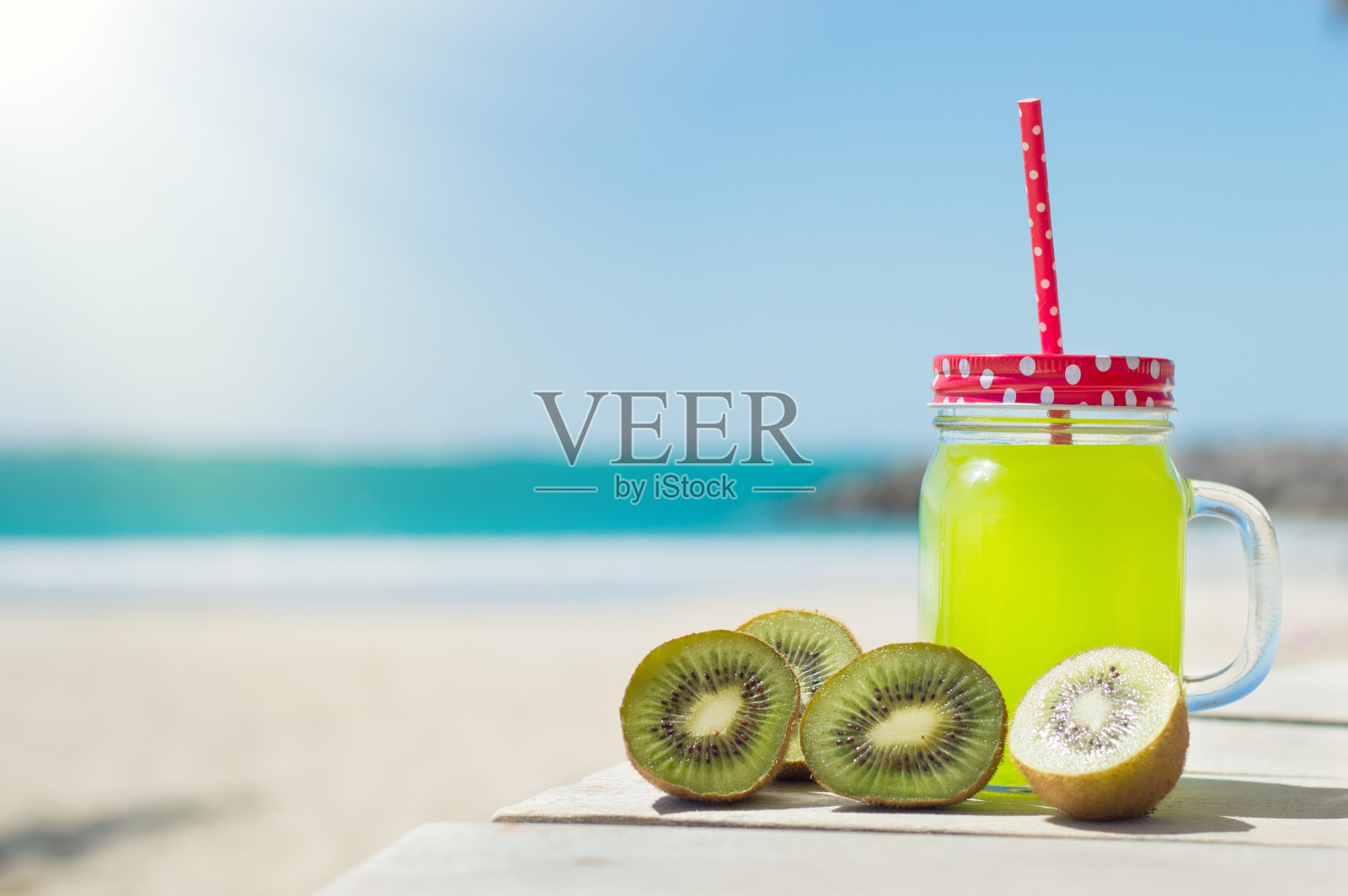 新鲜的果汁和猕猴桃片，海滩为背景照片摄影图片