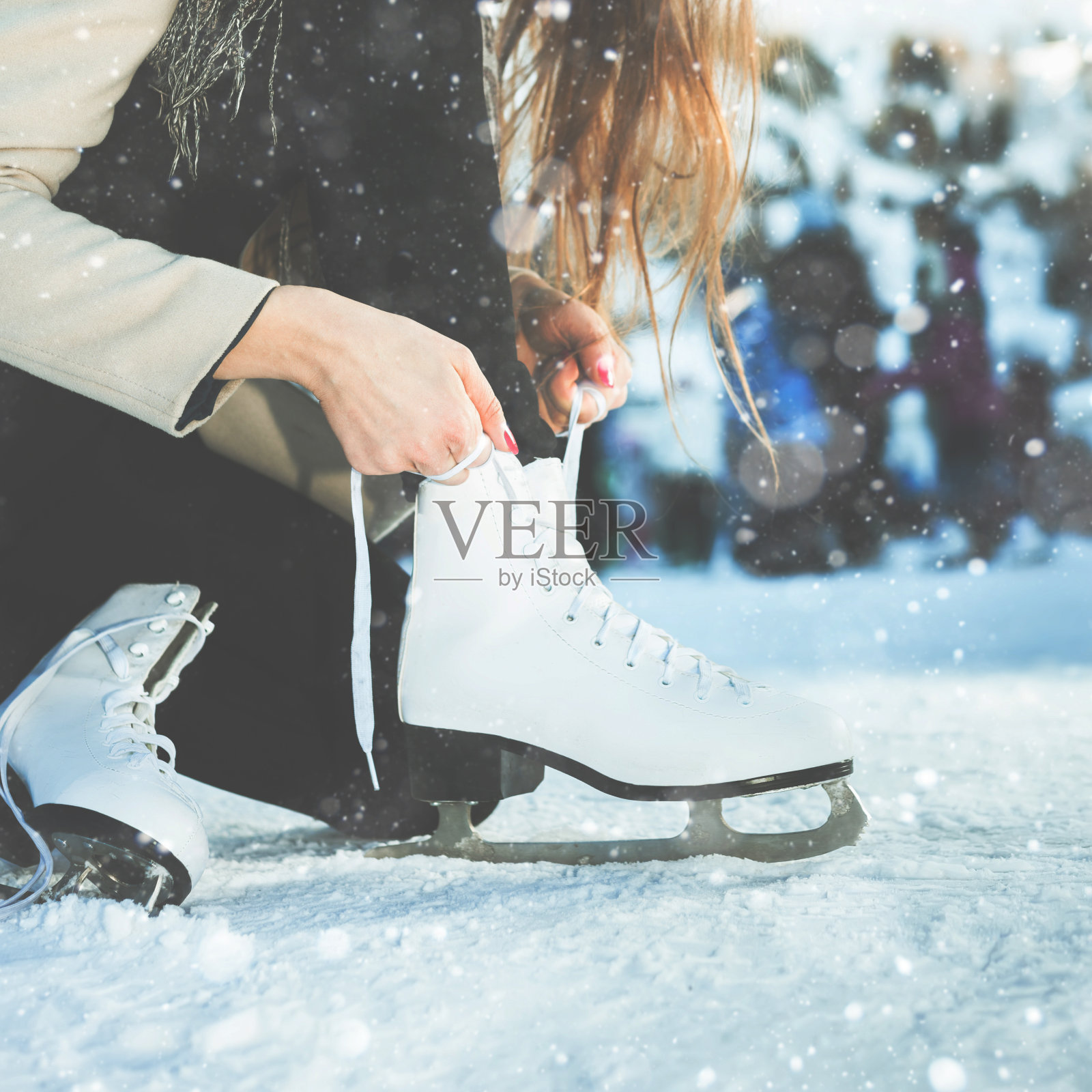 女人系鞋带在冰场的花样滑冰特写照片摄影图片