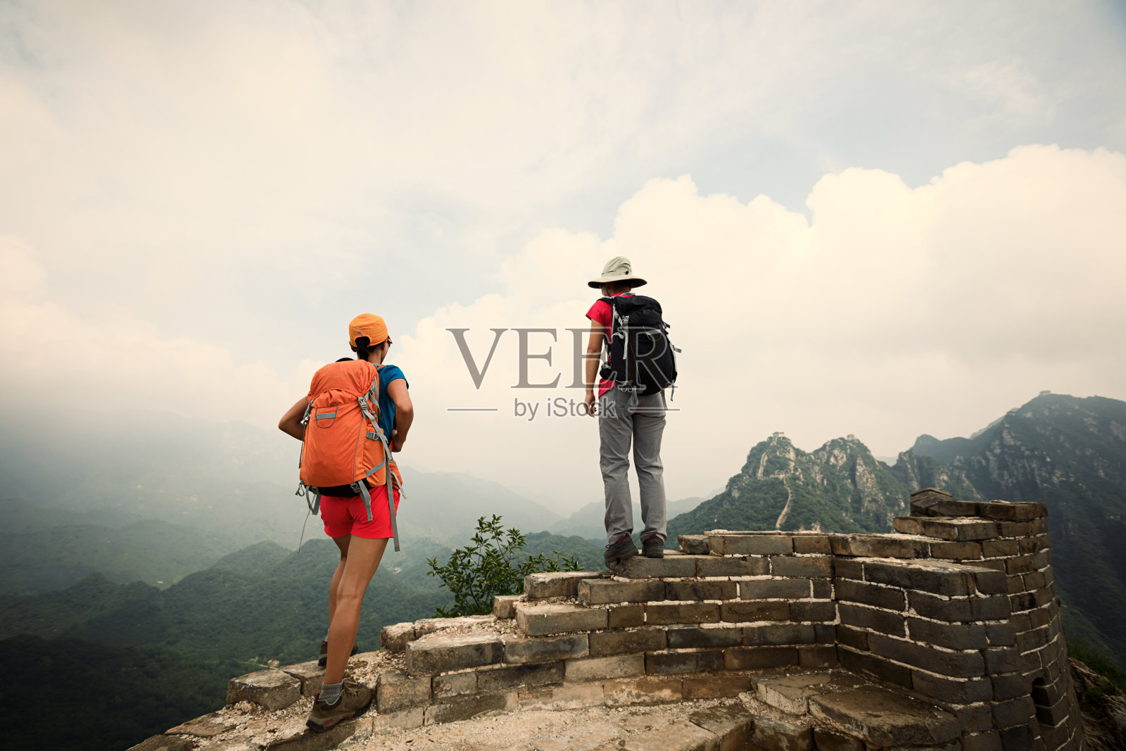 两位成功的女性徒步旅行者在长城顶上欣赏风景照片摄影图片