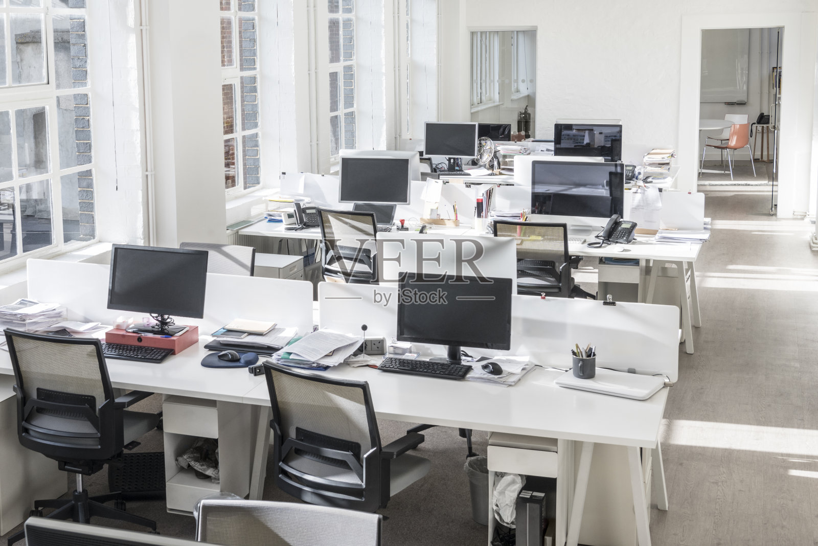 高角度的观点，凌乱的办公桌在现代办公室与空白电脑屏幕照片摄影图片