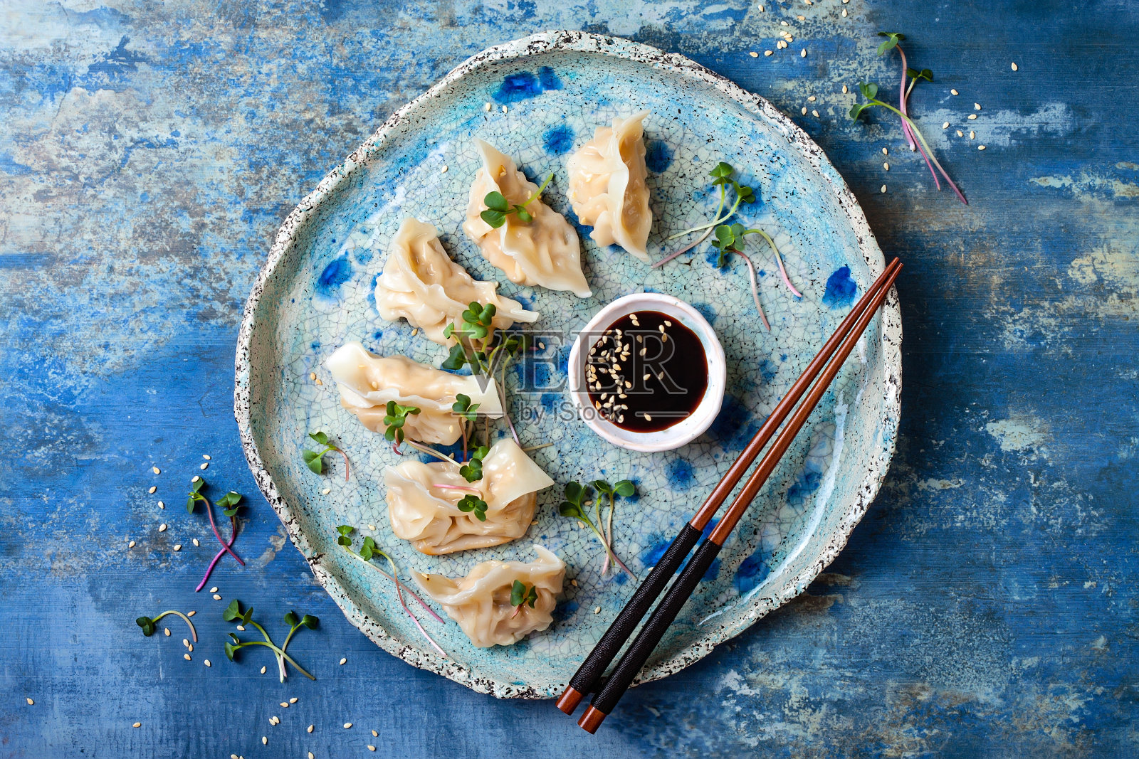 用酱油、芝麻和绿色蔬菜做成的亚洲饺子。传统的中国点心饺子。复制空间，平铺照片摄影图片