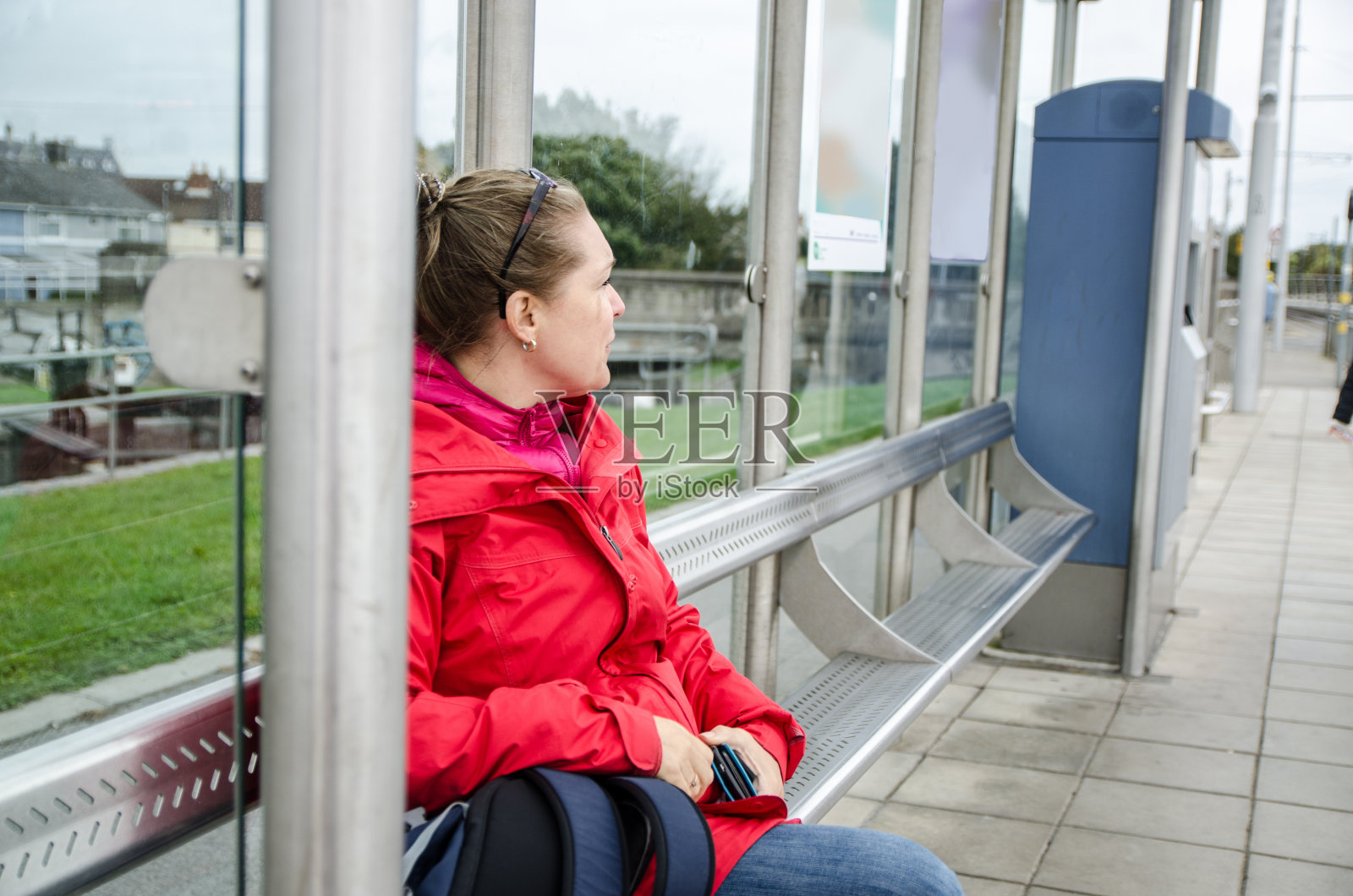秋日，在车站坐着等火车或公共汽车的妇女照片摄影图片