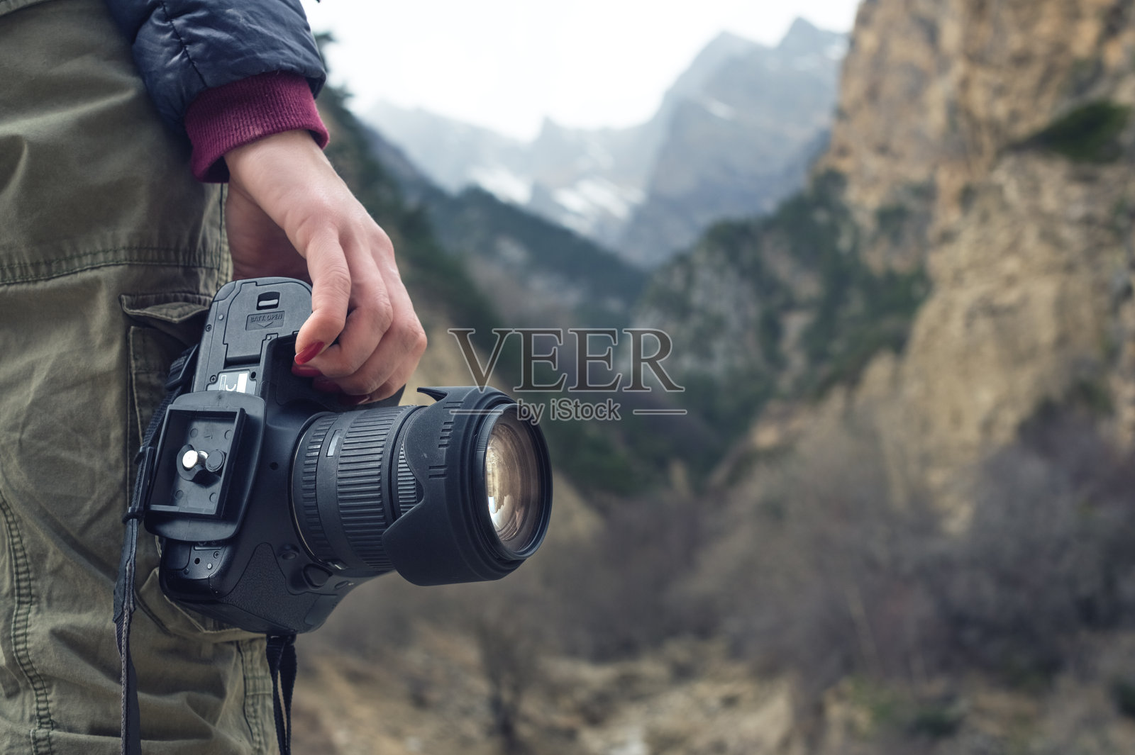 一位女性手持相机，背靠山景照片摄影图片