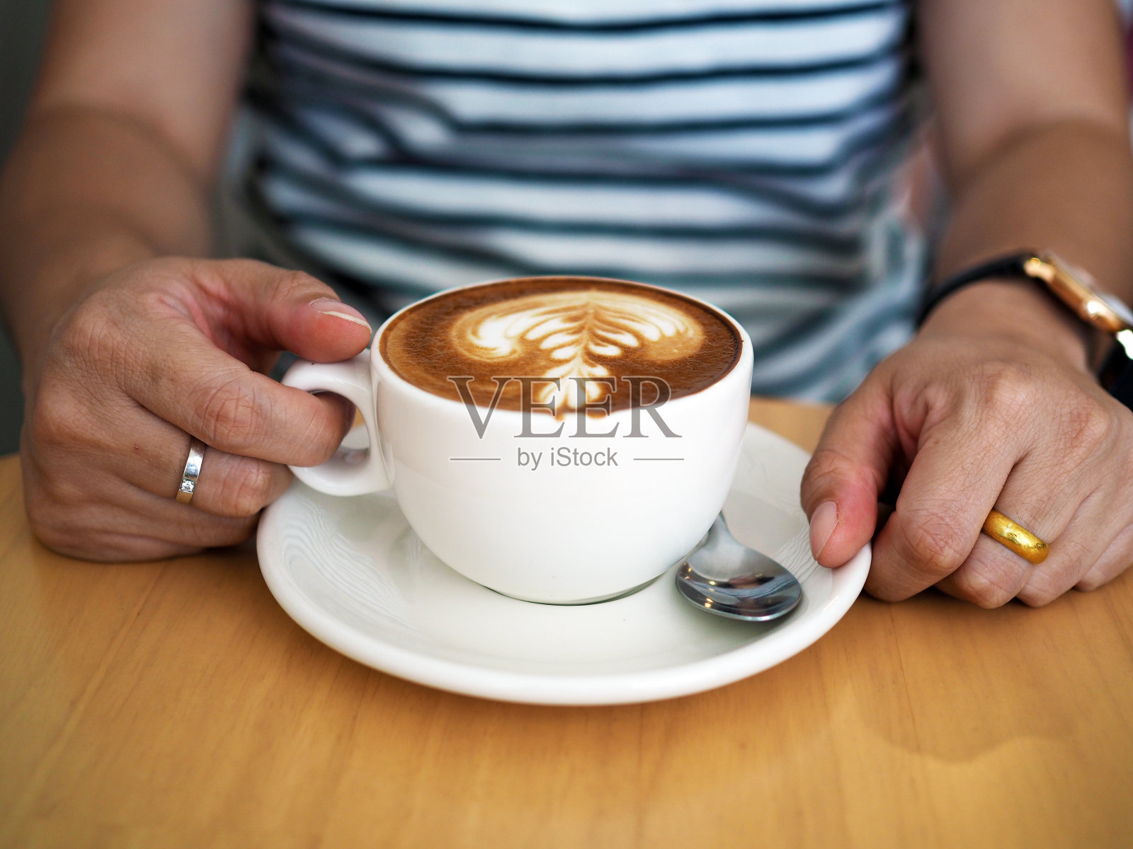 一杯美丽的热咖啡，拉花艺术和植物壶的木桌背景。照片摄影图片