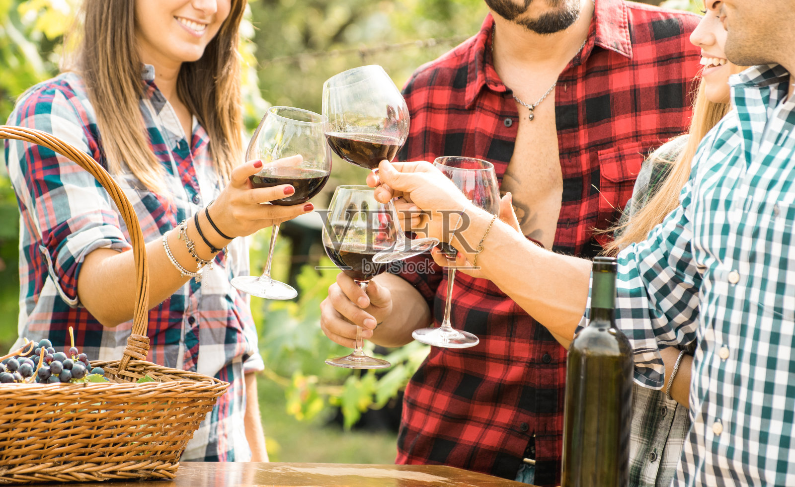 年轻的朋友们在户外畅饮红酒-开心的人在农家葡萄园里吃葡萄，在收获的时候喝酒-年轻的友谊理念与浅的深度的田野照片摄影图片