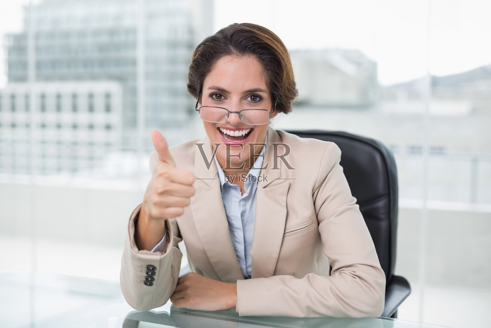 愉快的女商人在她的办公桌前竖起大拇指照片摄影图片