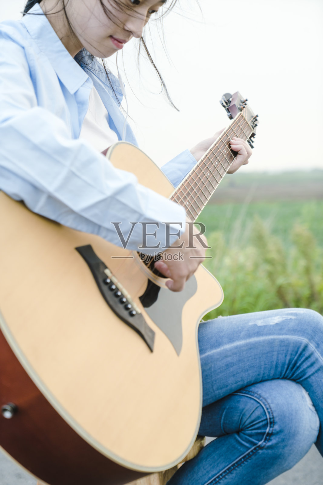 女人的手在田野里弹吉他的特写照片摄影图片