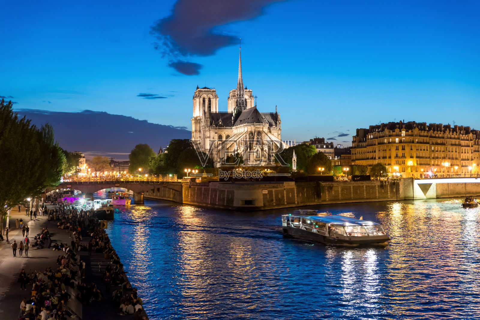 巴黎圣母院与游船在塞纳河上的夜晚，法国巴黎照片摄影图片