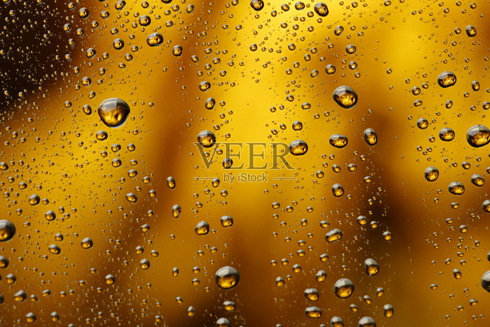 冰冷的玻璃覆盖着水滴凝结冷饮水滴金色的黄色-橙色的饮料背景雨点纹理近照片摄影图片