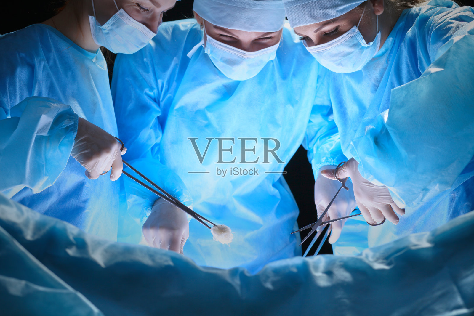 一组在手术室工作的外科医生，色调为蓝色照片摄影图片