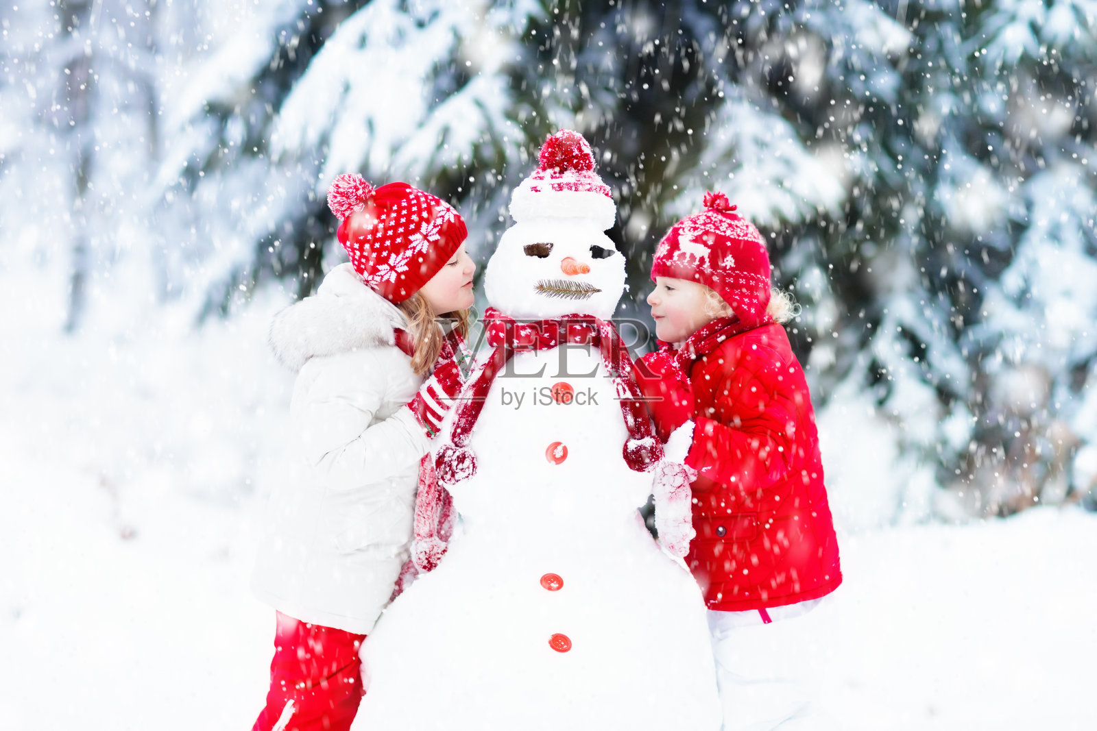 孩子们建造雪人。孩子们在雪。冬天的乐趣。照片摄影图片