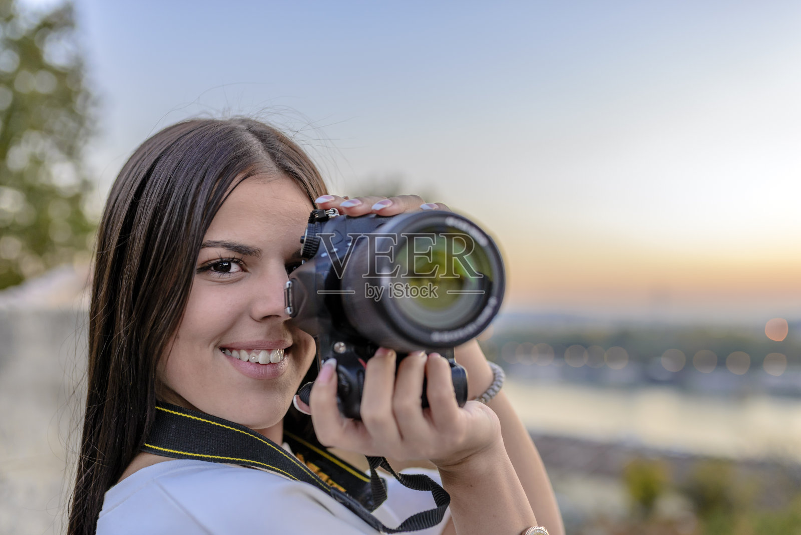 一名女摄影师拿着相机靠近她的脸拍照照片摄影图片