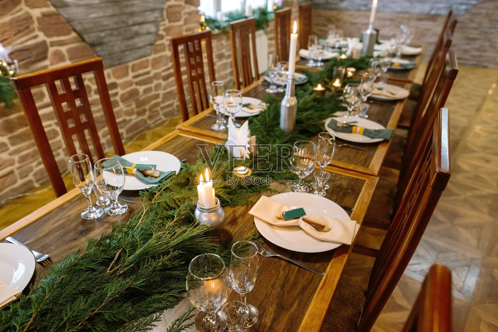 冬天，气氛，庆祝的概念。餐厅里有一件由天然材料制成的优雅家具，长桌用云杉树枝和蜡烛装饰照片摄影图片