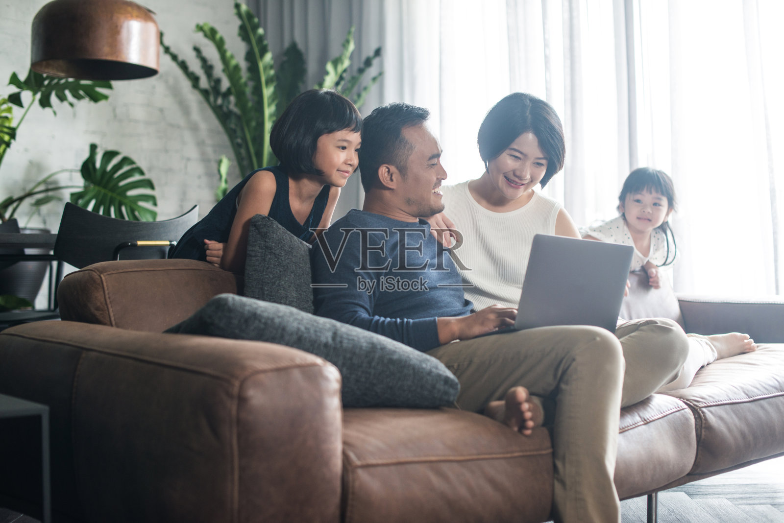 亚洲家庭在家里看电脑。照片摄影图片