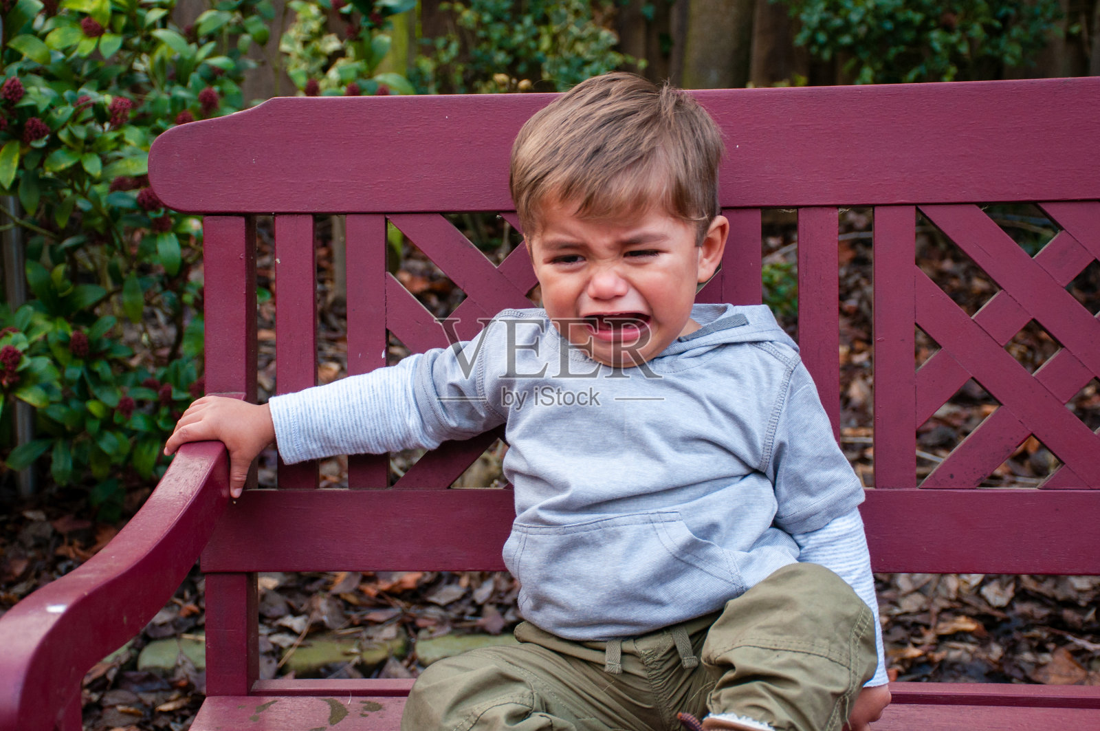 坐在长凳上哭闹的小孩照片摄影图片