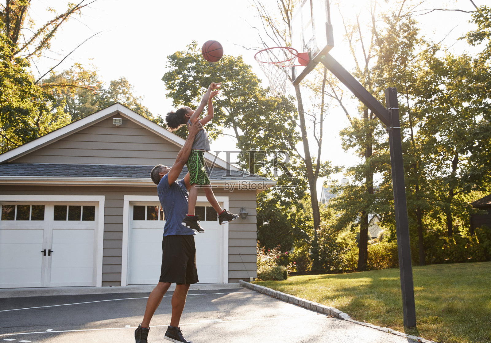 爸爸和儿子在家里的车道上打篮球照片摄影图片