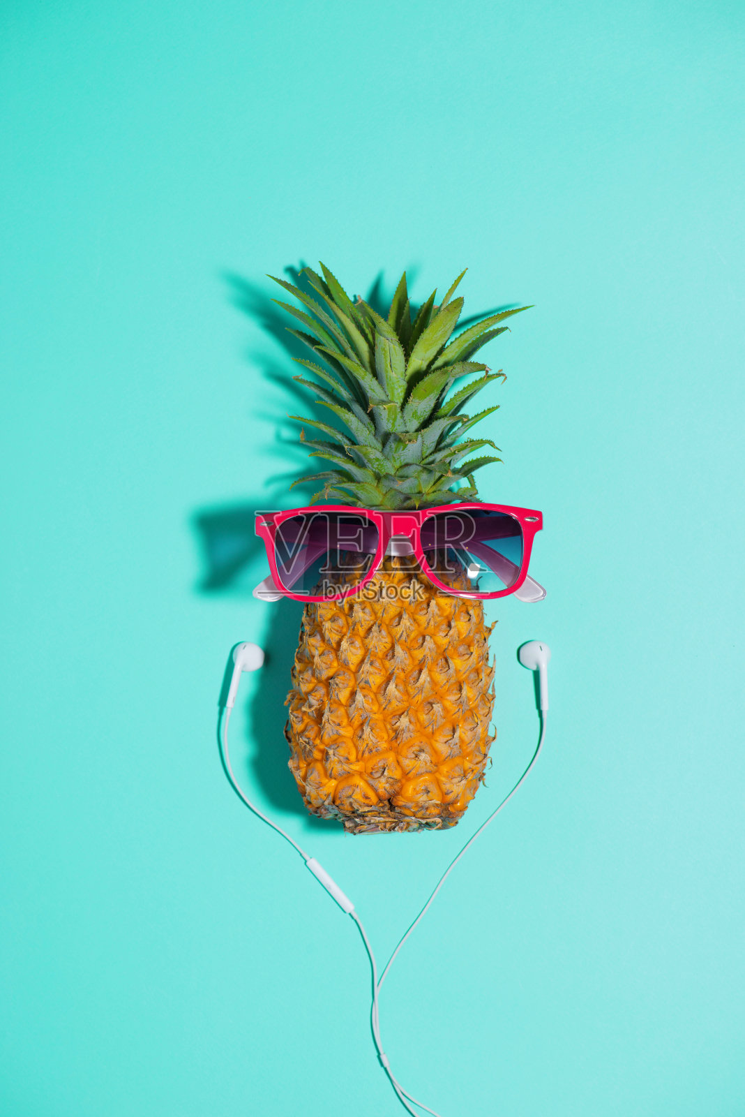 时尚菠萝戴着太阳镜和耳机在蓝色背景下听音乐照片摄影图片