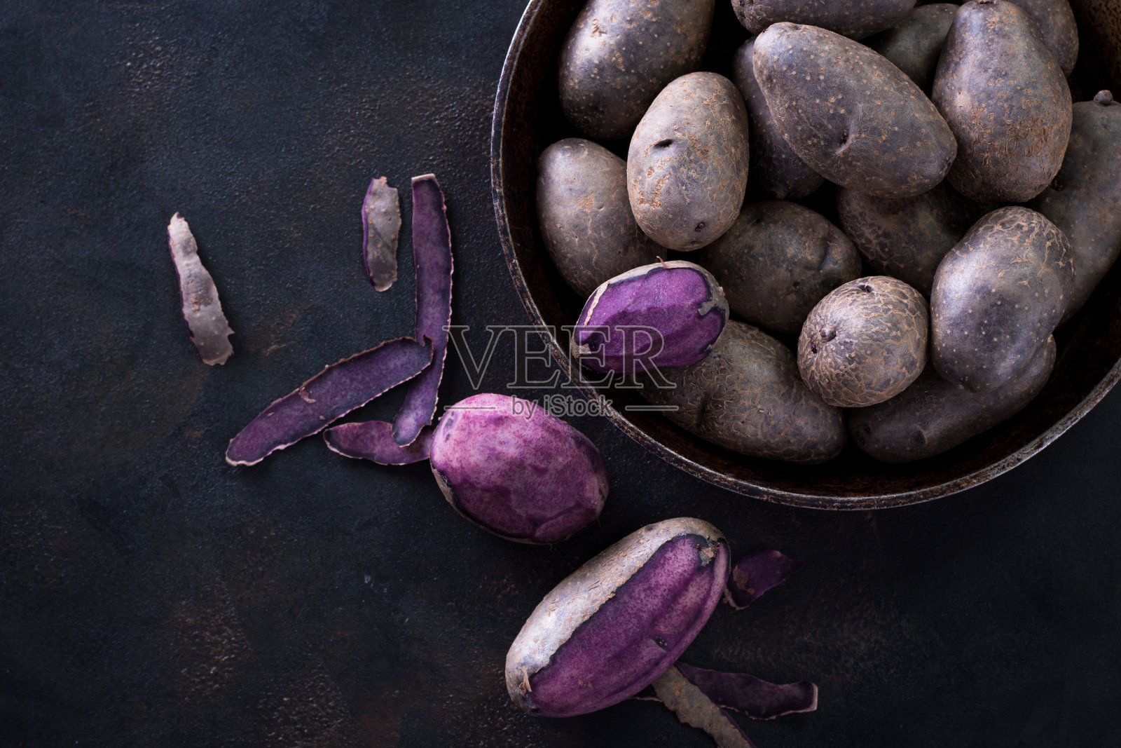 生土豆食品。黑色背景上的新鲜蓝土豆。文本的自由空间。照片摄影图片
