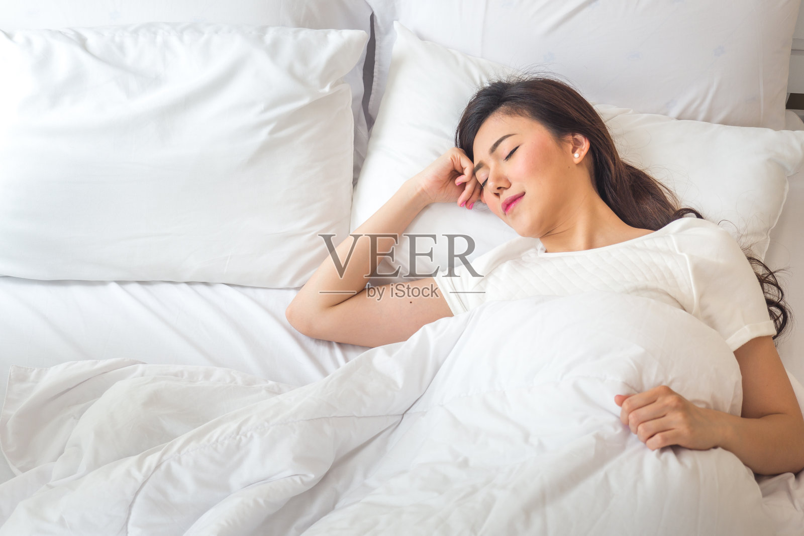 美丽的亚洲女人睡在白色的床上与幸福的感觉照片摄影图片